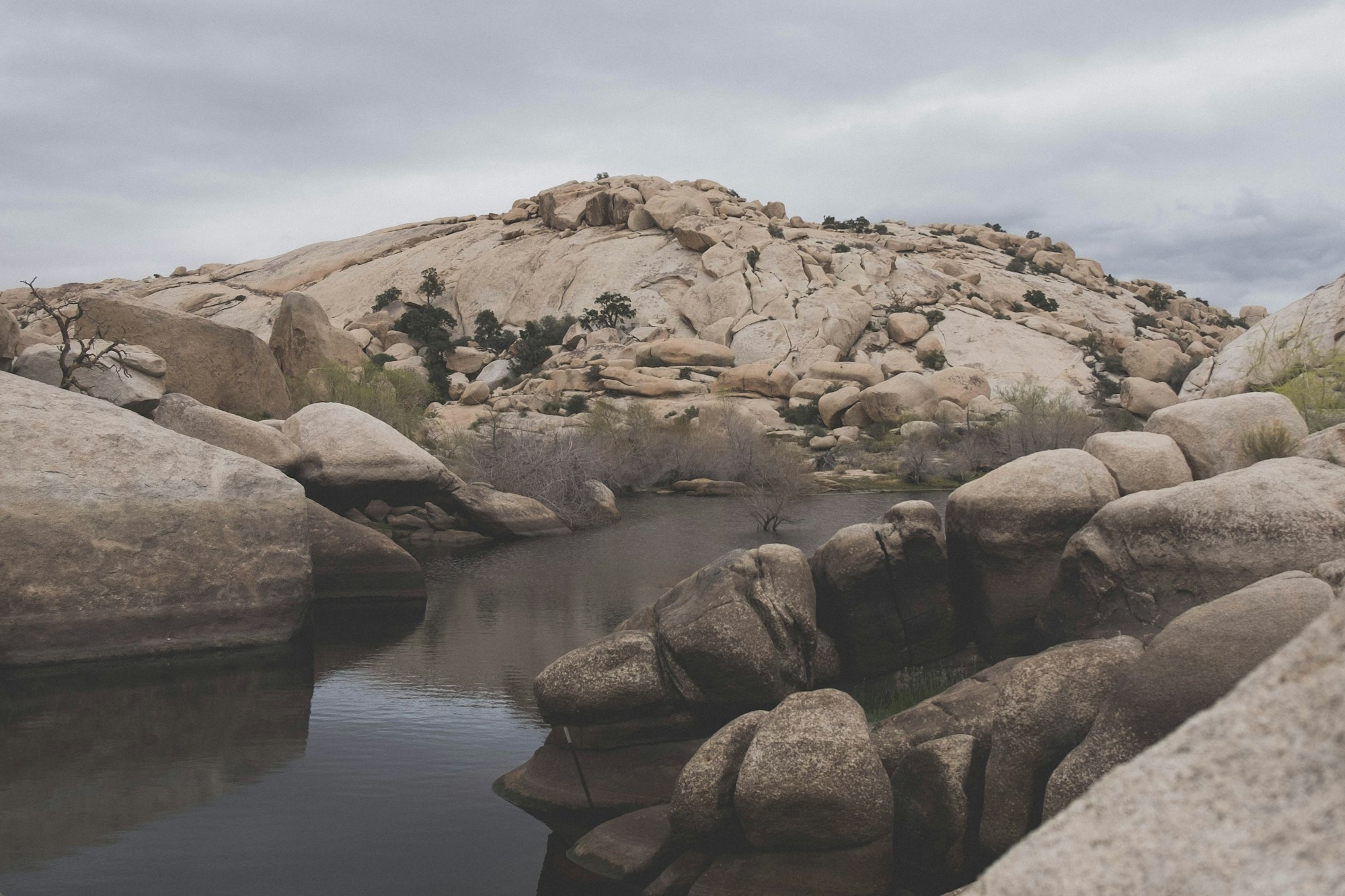 Barker Dam surrounded by boulders under a cloudy sky in Joshua Tree National Park