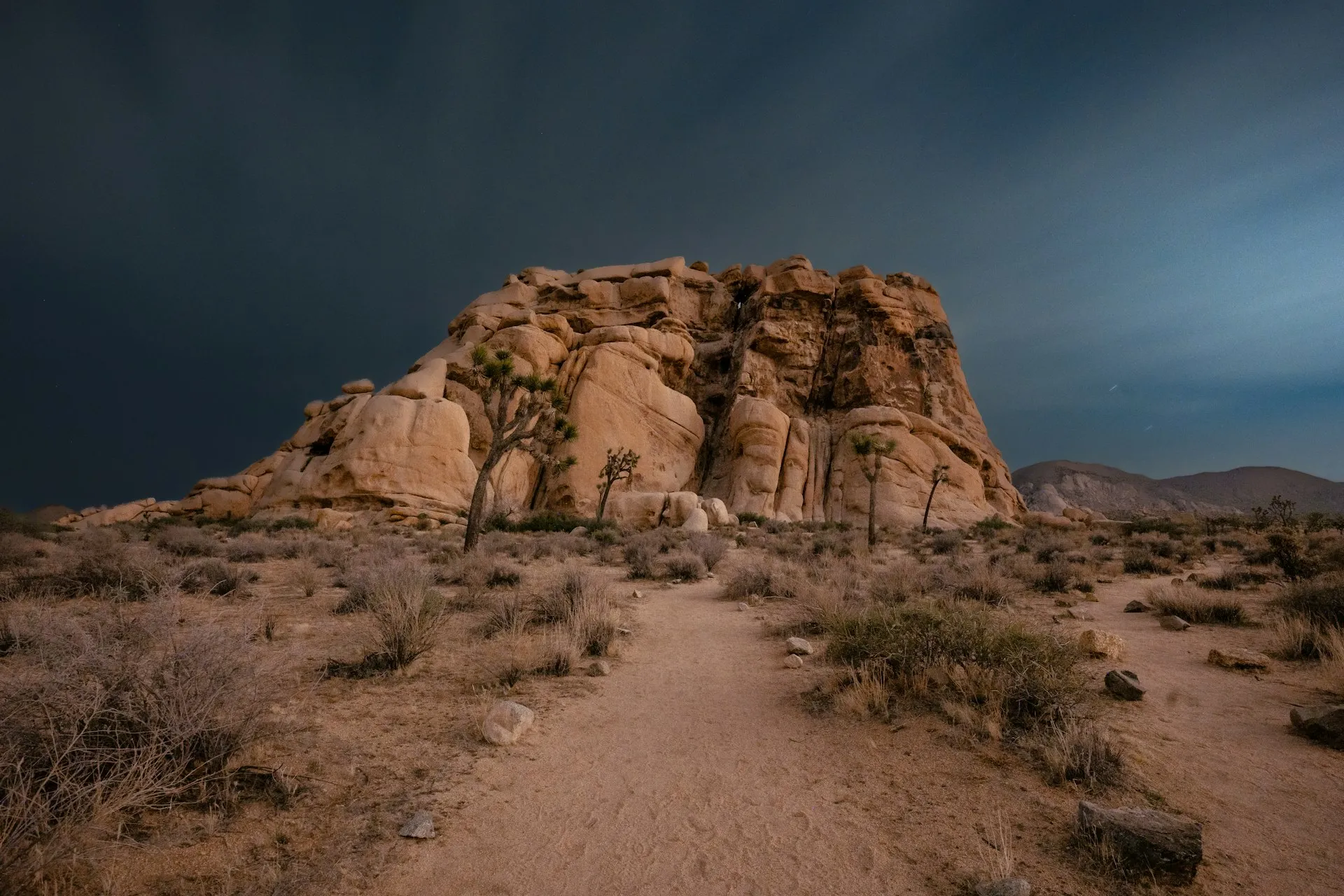 Dramatic rock formation in Joshua Tree under a moody desert sky