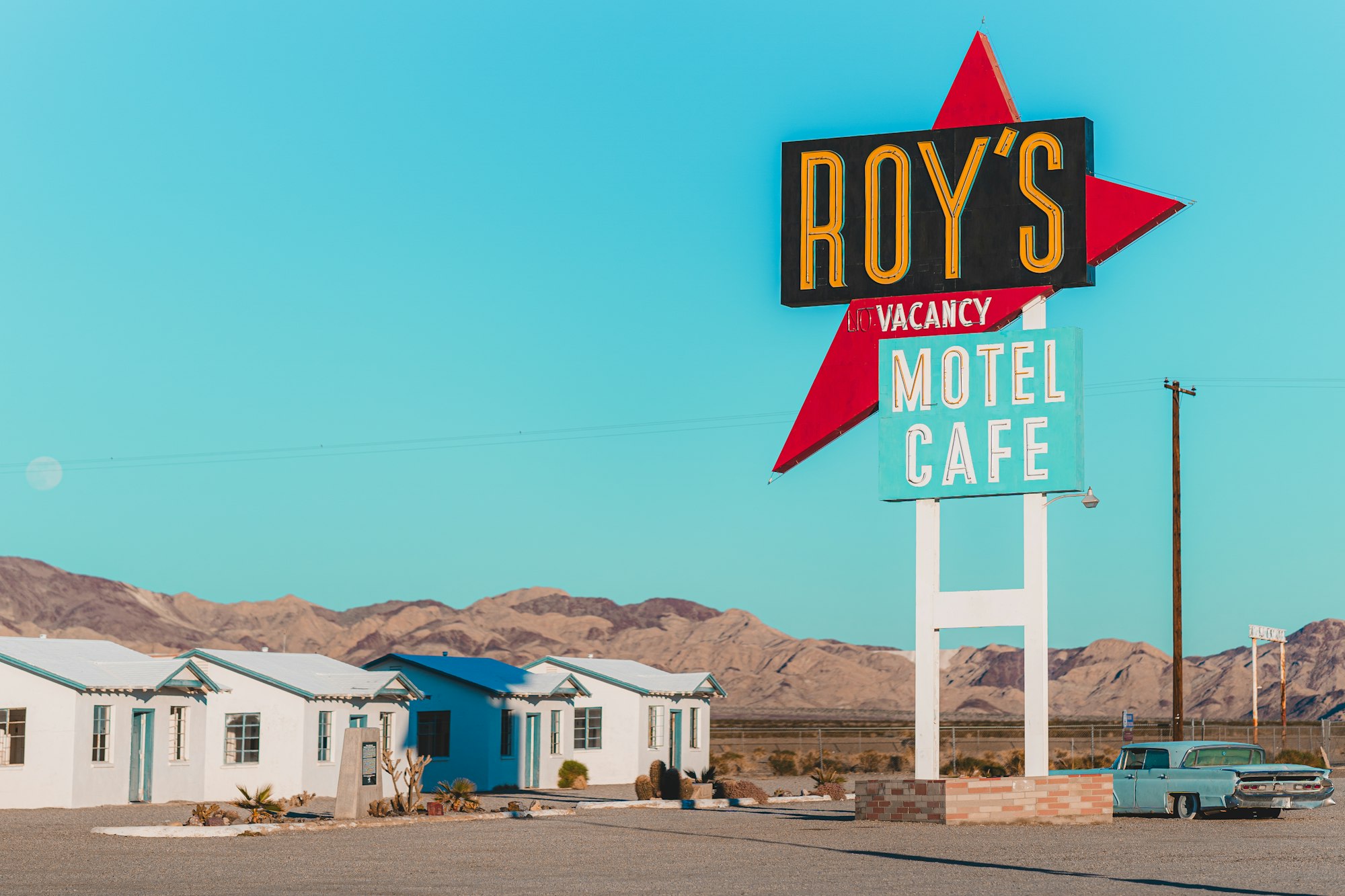 Vintage desert motel sign with a car parked beneath it